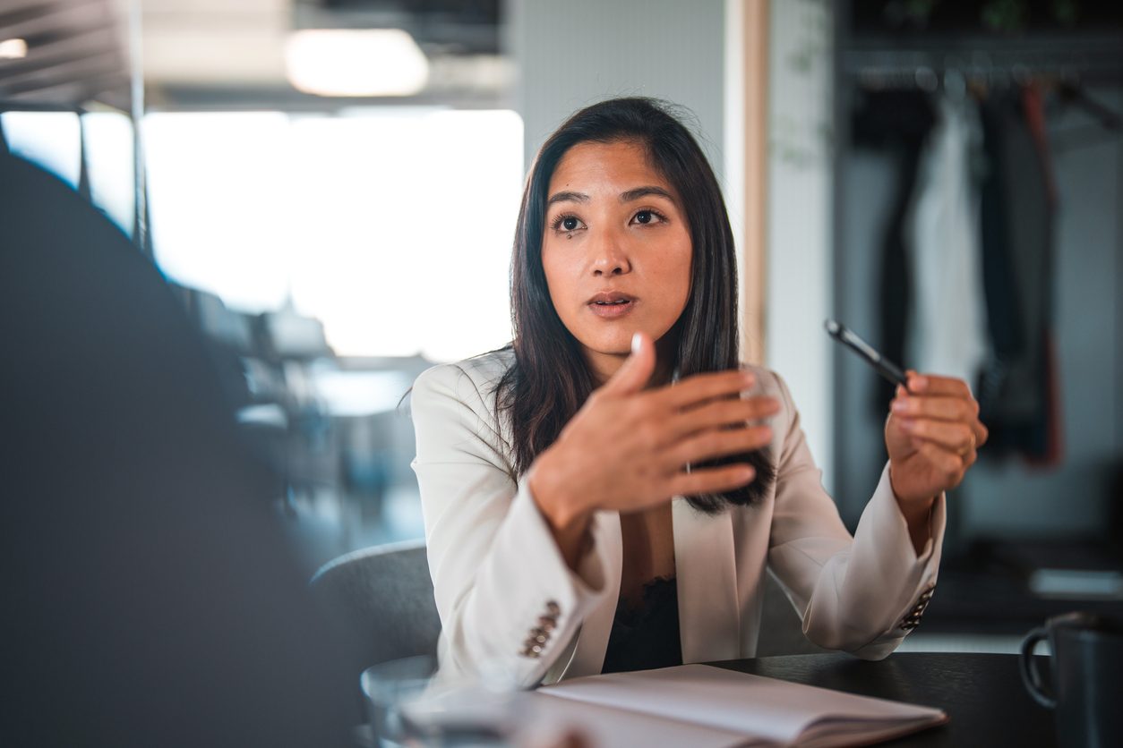 Asian woman holding pen negotiates with unseen person