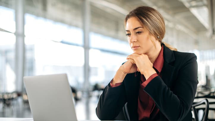 A business woman sitting at a desk looking at her laptop.