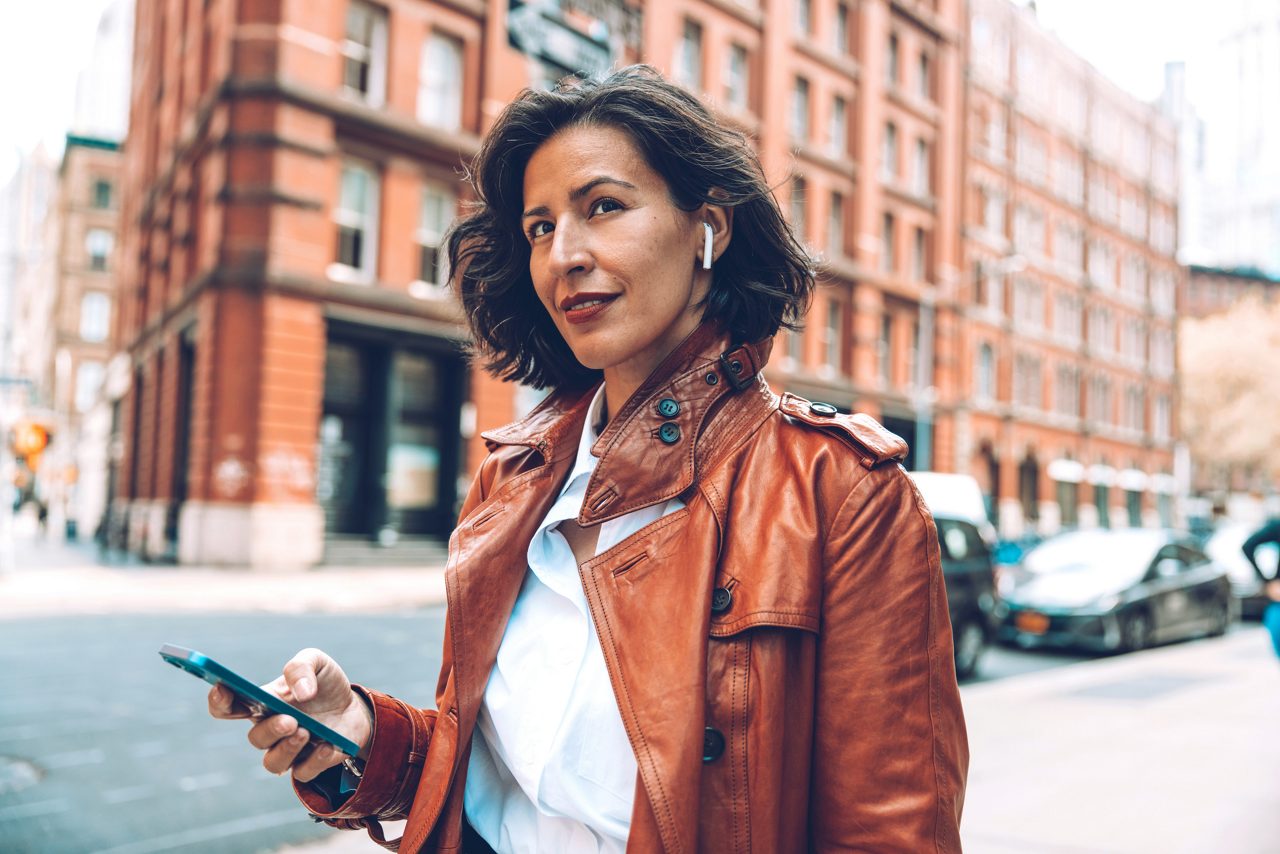 Elegant businesswoman walking to the office listening voice messages on earphones in downtown New York.