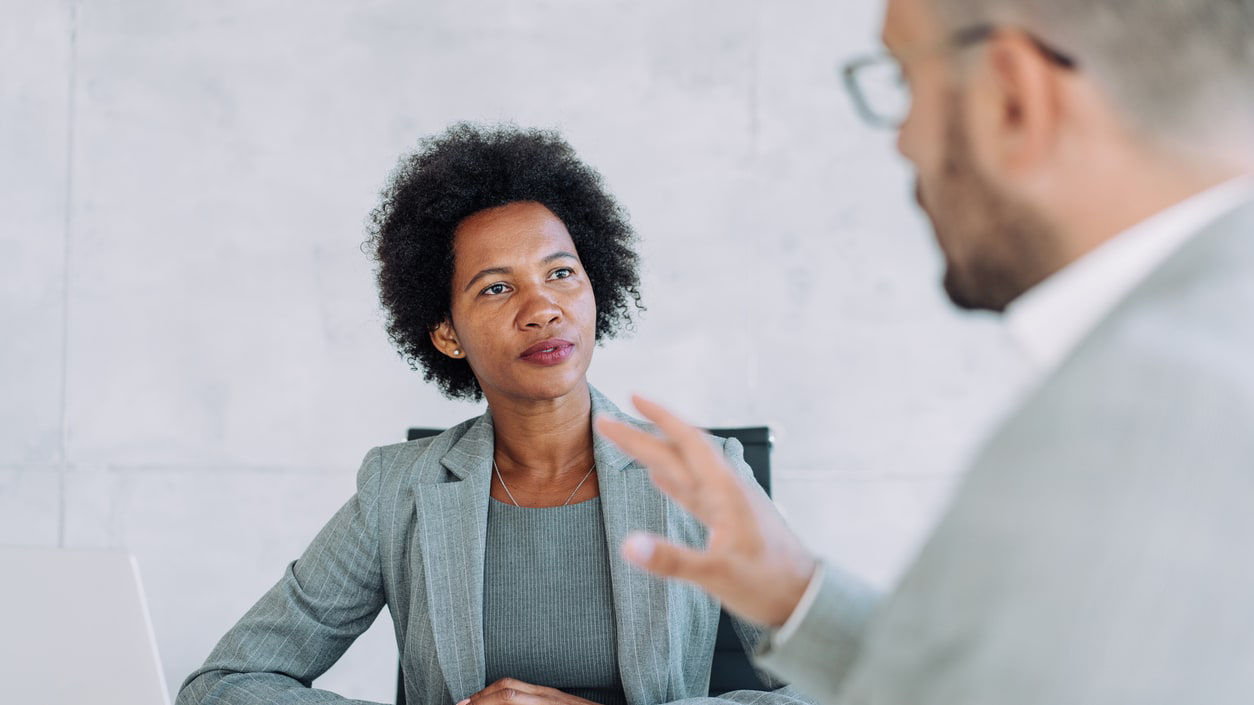 A businesswoman talking to a businessman in an office.
