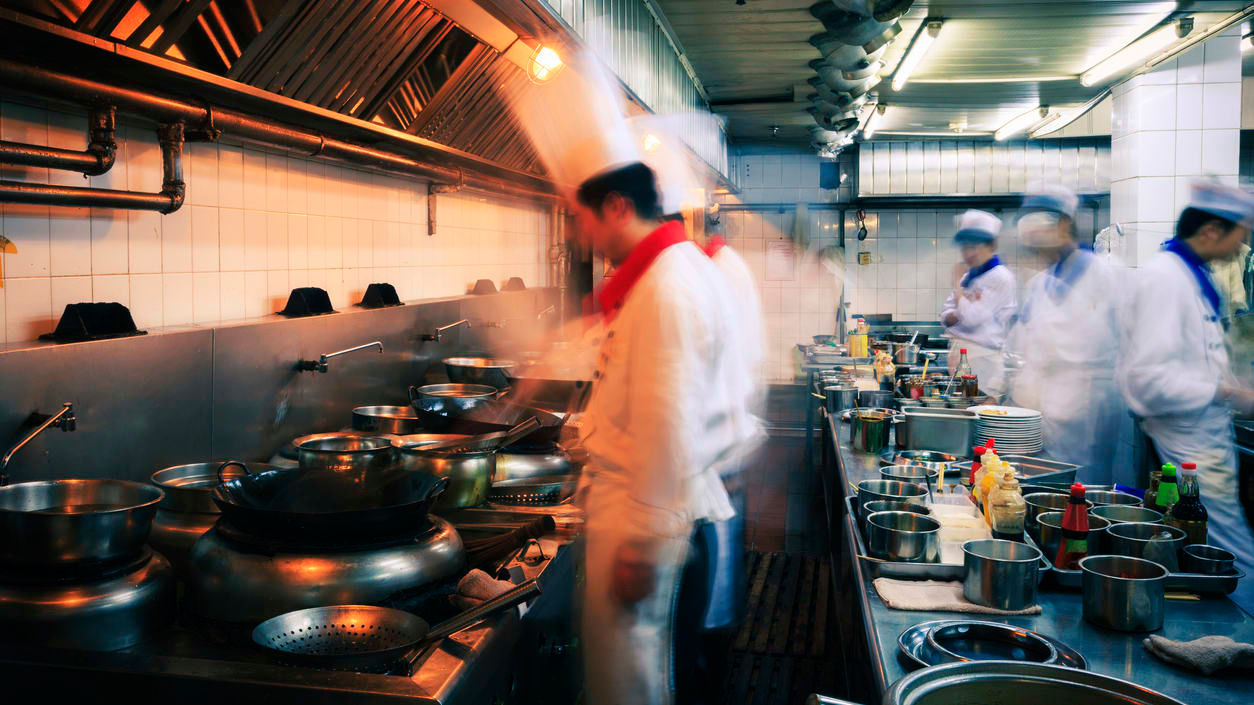 A blurry image of a group of cooks in a kitchen.