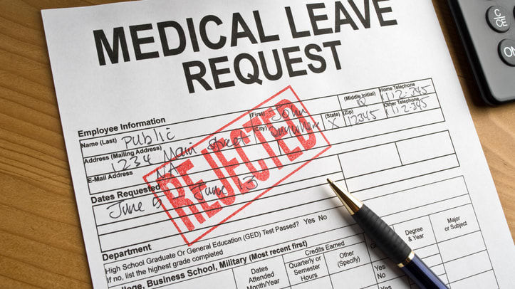 A medical leave request form on a desk with a pen and calculator.