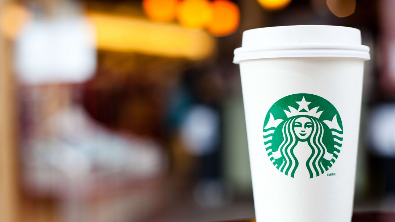 A starbucks coffee cup sits on a table.