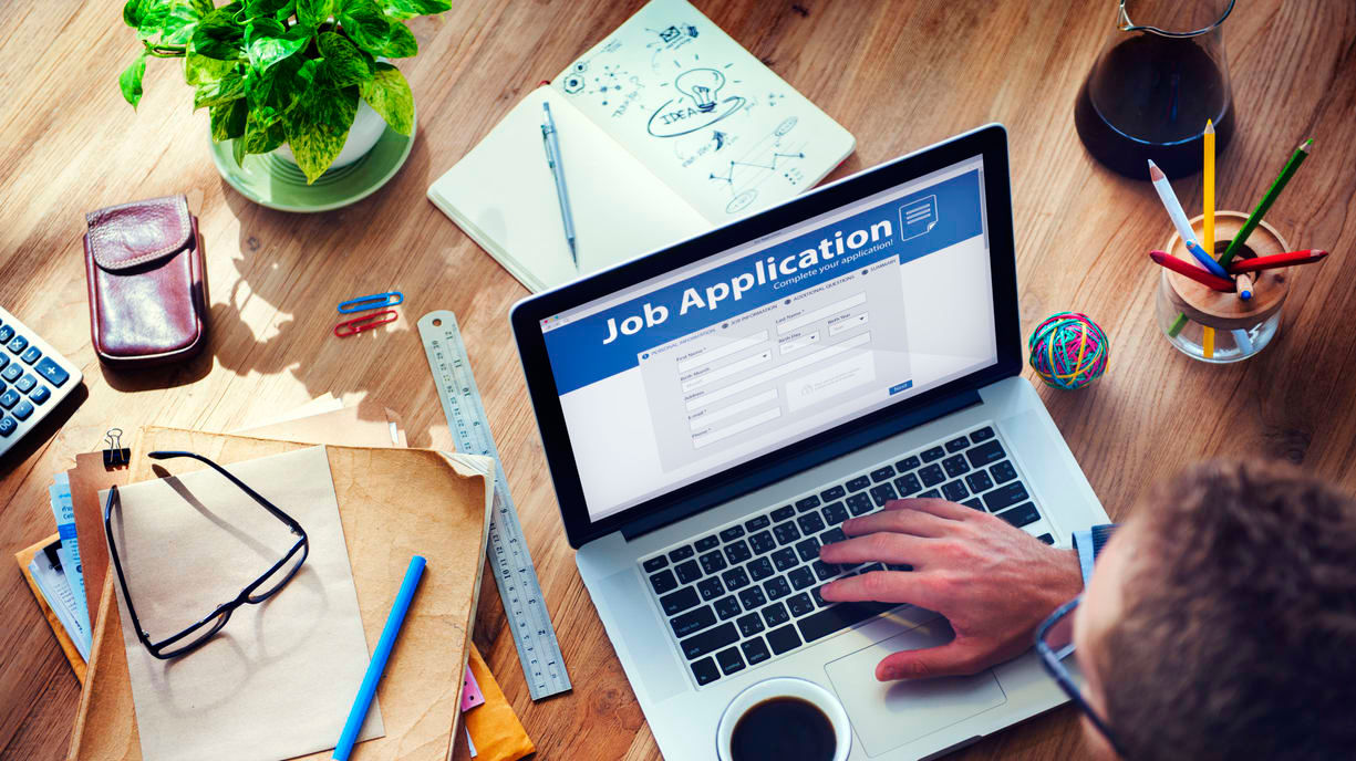 A man is using a laptop to fill out a job application.