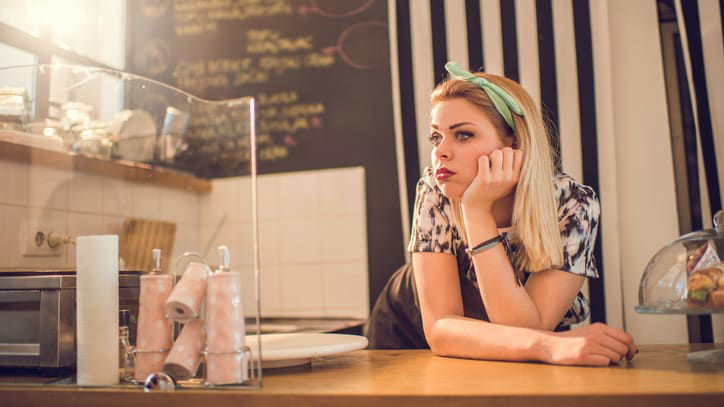 A woman leaning over a counter in a coffee shop.