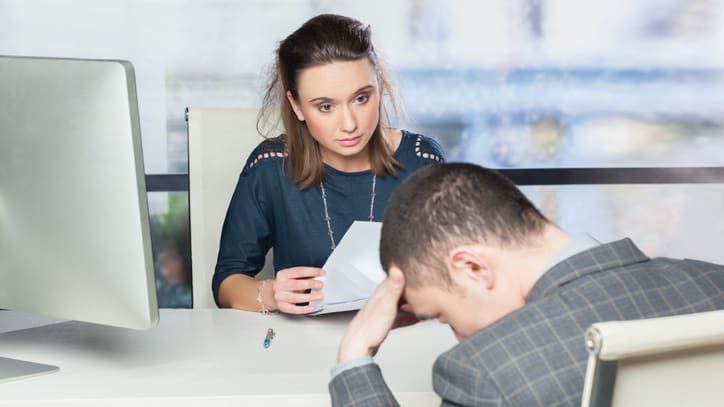 A man and woman sitting at a desk in an office.