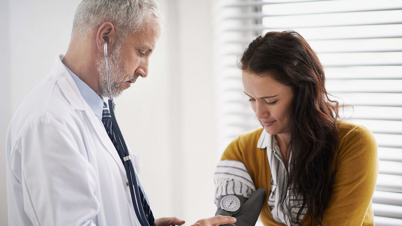 A doctor is checking a woman's blood pressure.