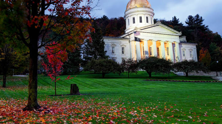 A large white building sits in the middle of a grassy field.