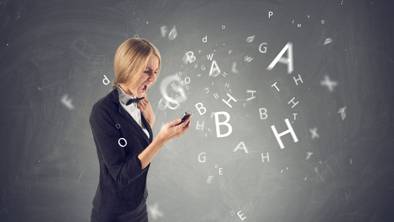 A business woman is holding a cell phone with letters coming out of it.