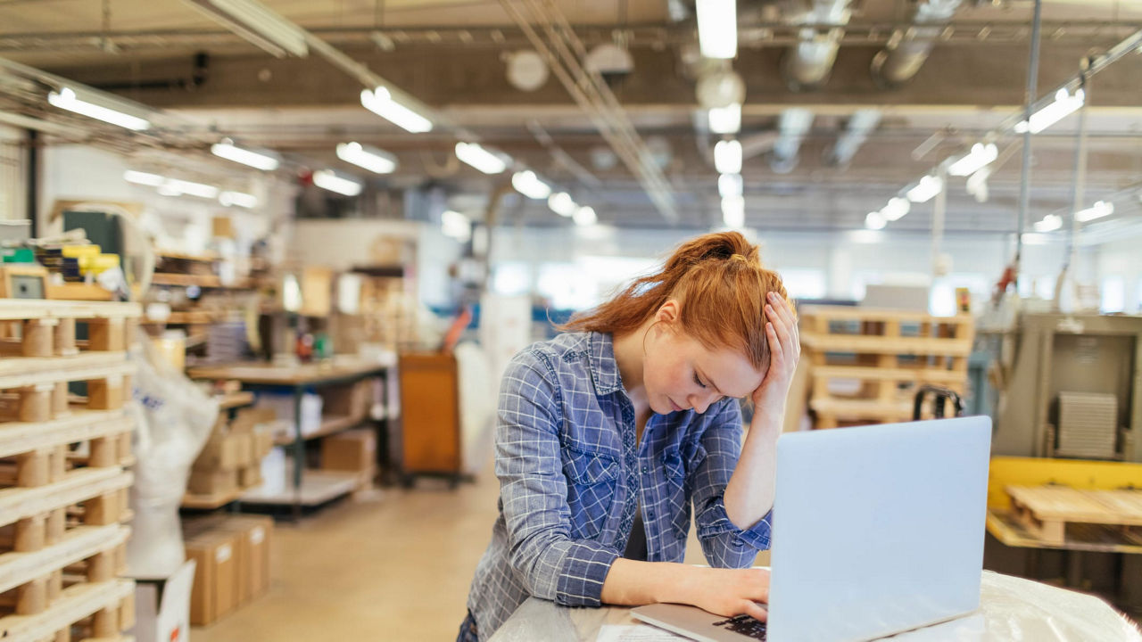 A woman working on a laptop in a warehouse.