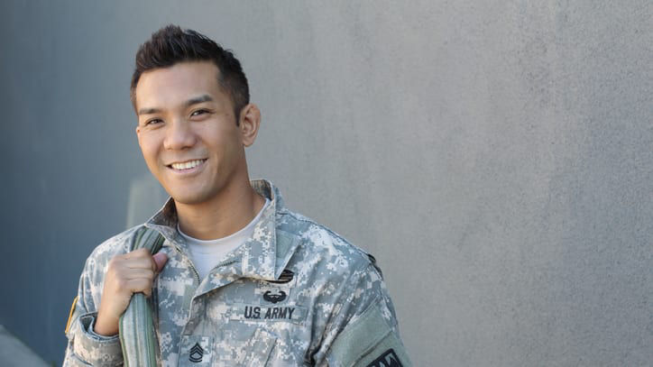 A young man in military uniform smiling.