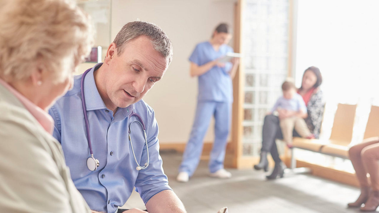 A doctor is talking to an elderly woman in a waiting room.