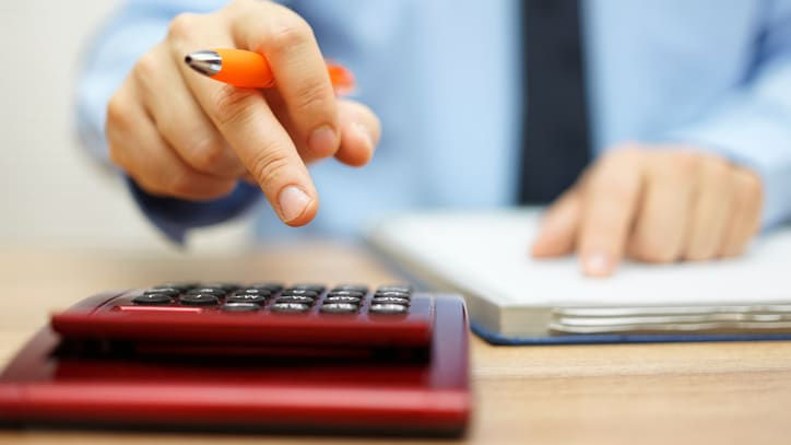 A man is holding a calculator and a pen.