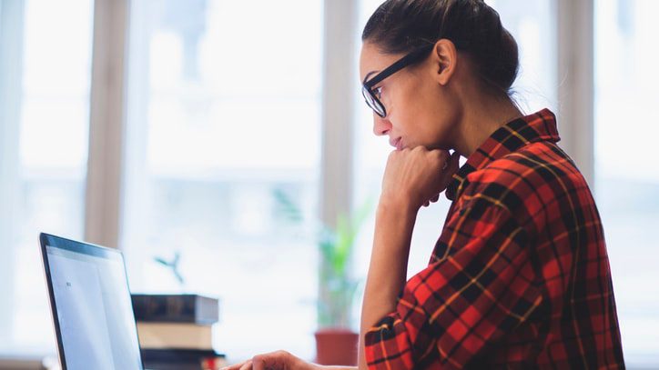 A woman working on a laptop in an office.