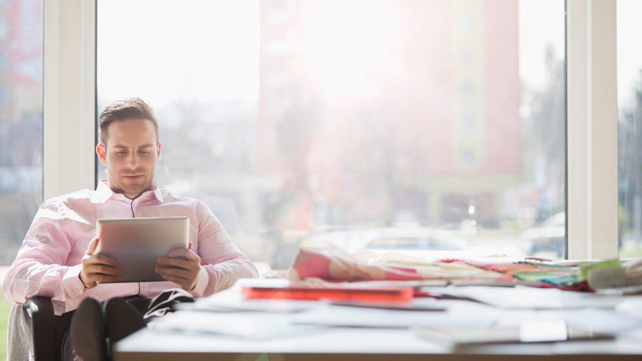 A man sitting at a desk using a tablet computer.