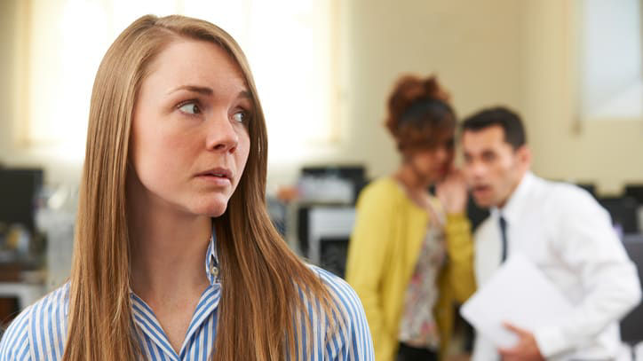 A woman is standing in an office with other people.