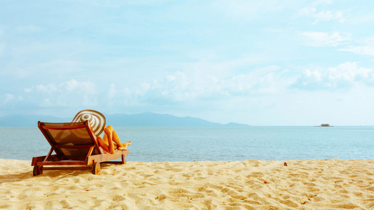 A woman relaxes on a beach chair in front of the ocean.