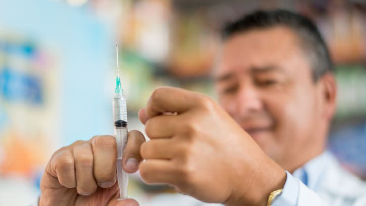 A man holding a syringe in a pharmacy.