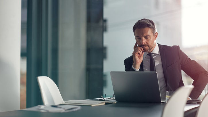 A businessman talking on the phone while sitting at a desk.
