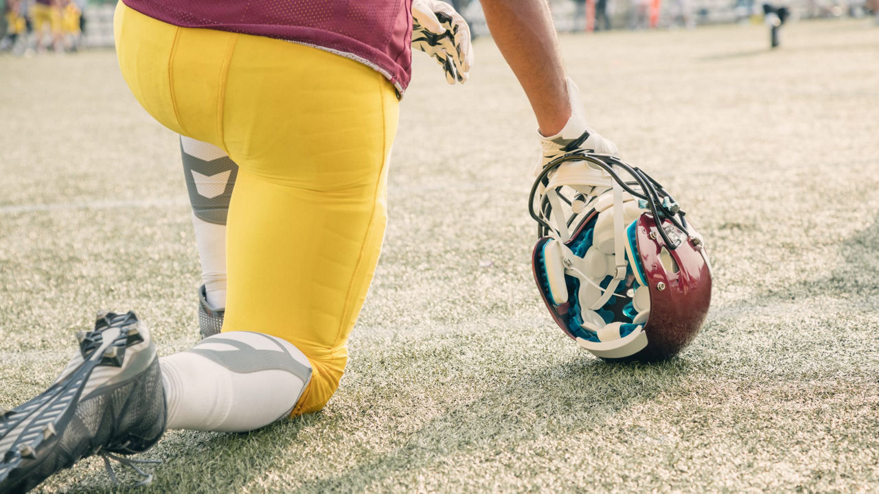 A football player kneeling down on the field.