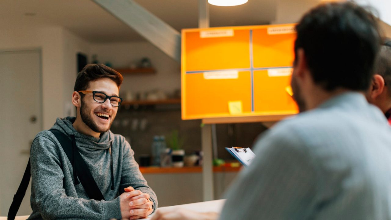 Two men sitting at a table talking to each other.