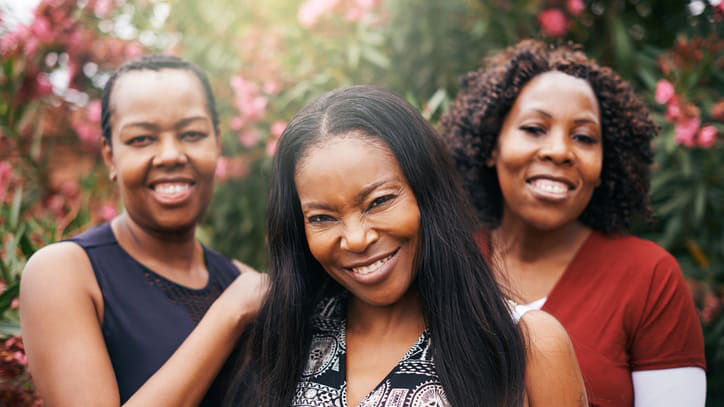 Three women friends posing for a photo in a garden.