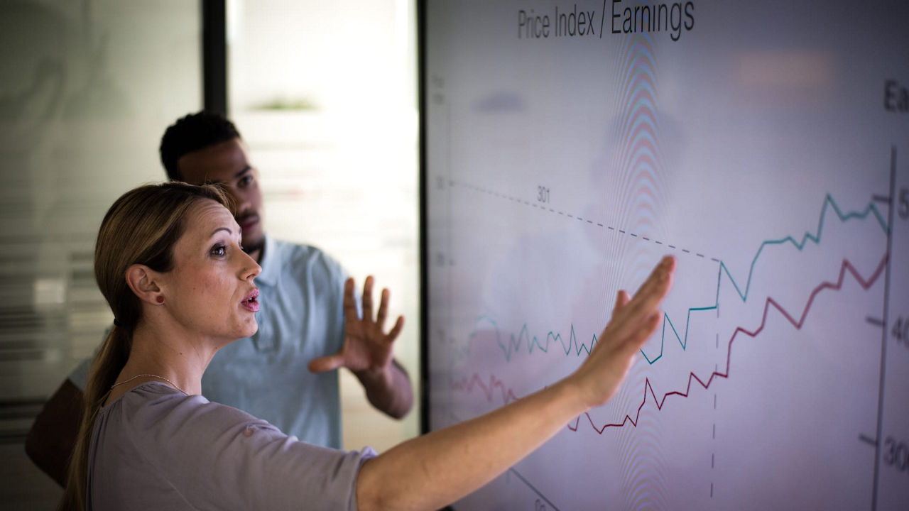 A man and woman pointing at a whiteboard.