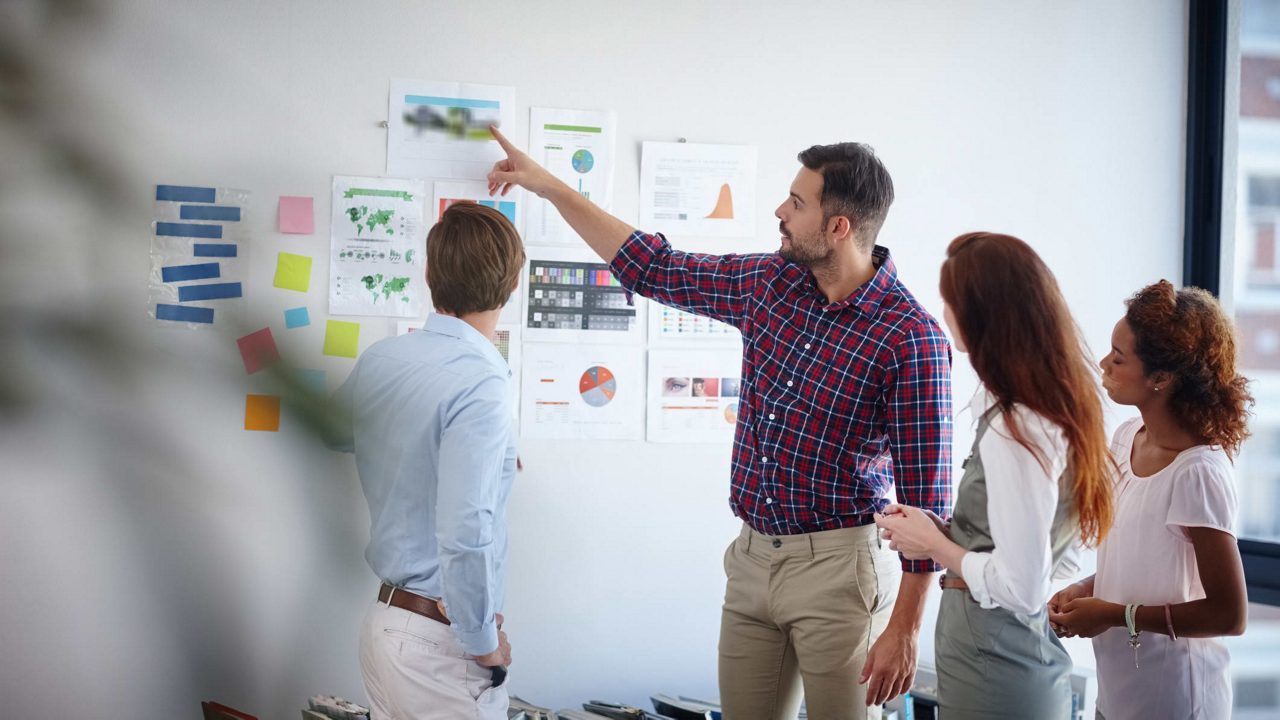 A group of people standing around a whiteboard.