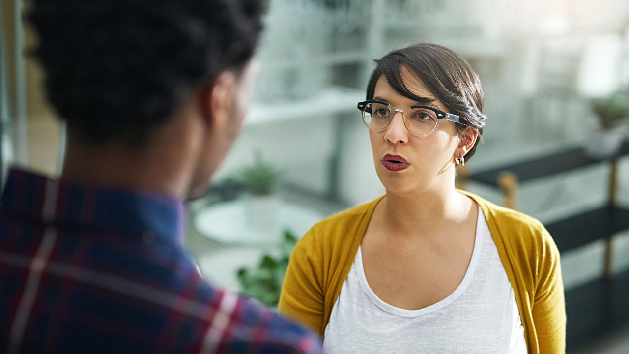 A woman is talking to a man in an office.