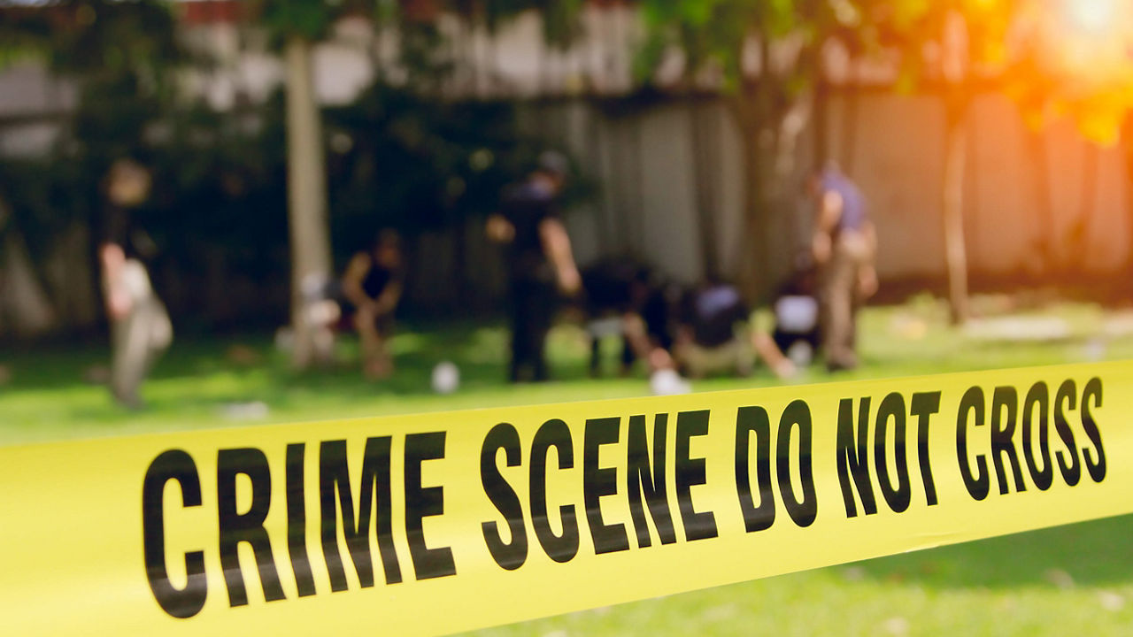 A yellow crime scene tape with people in front of it.