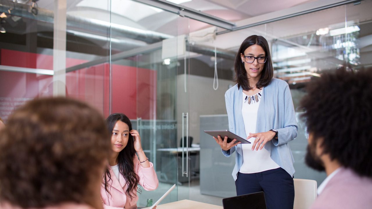 A woman is giving a presentation to a group of people in a conference room.