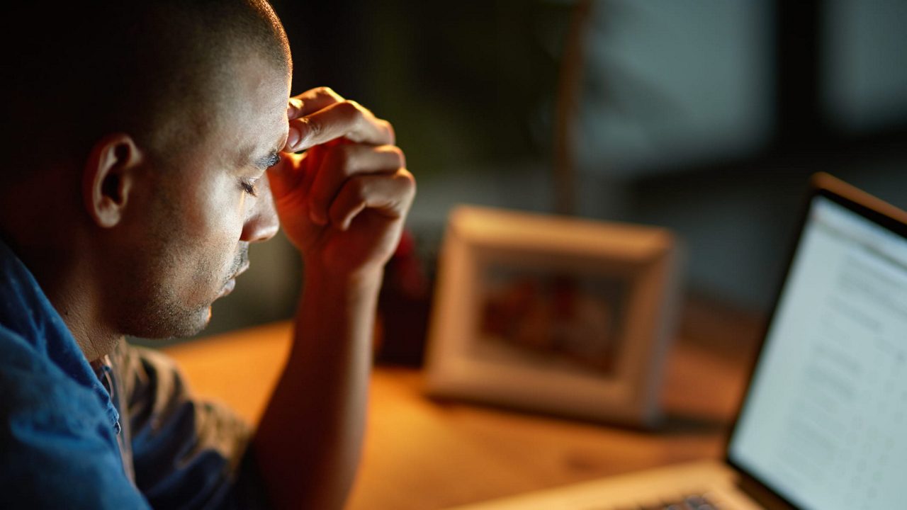 A man is looking at his laptop at night.