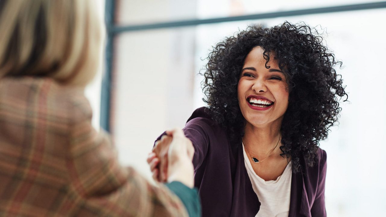 Two women shaking hands in an office.