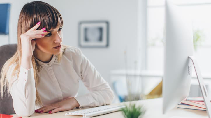 A woman is sitting at a desk with her head on her head.