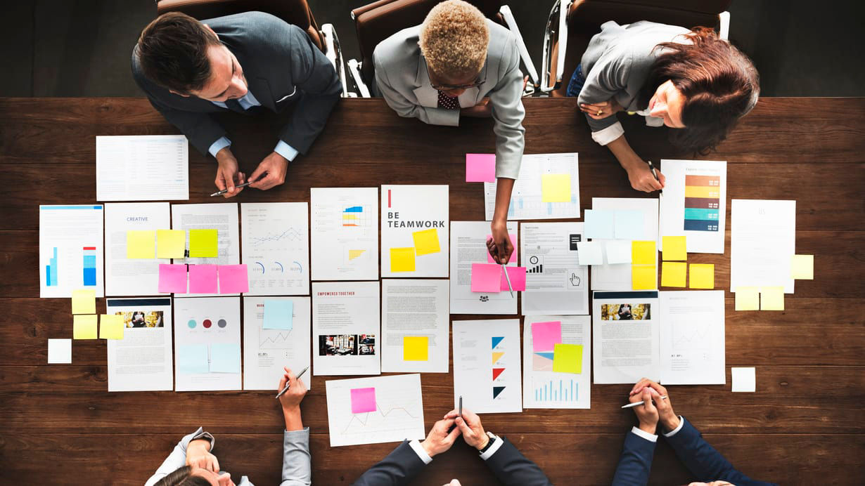 A group of business people sitting around a table with sticky notes.