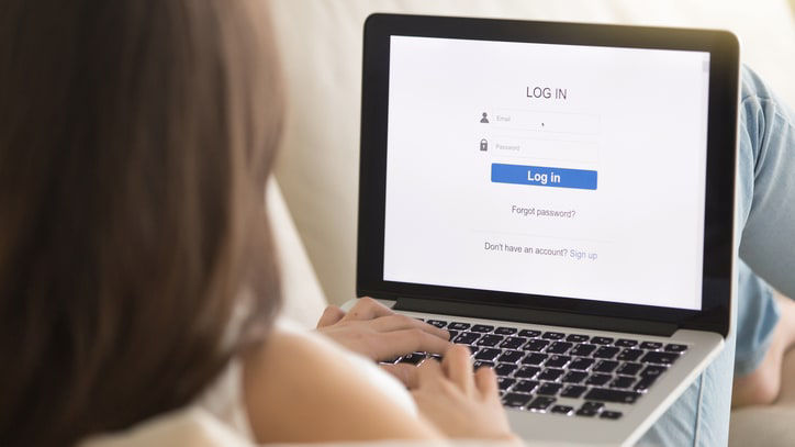 A woman sitting on a couch with a laptop on her lap.
