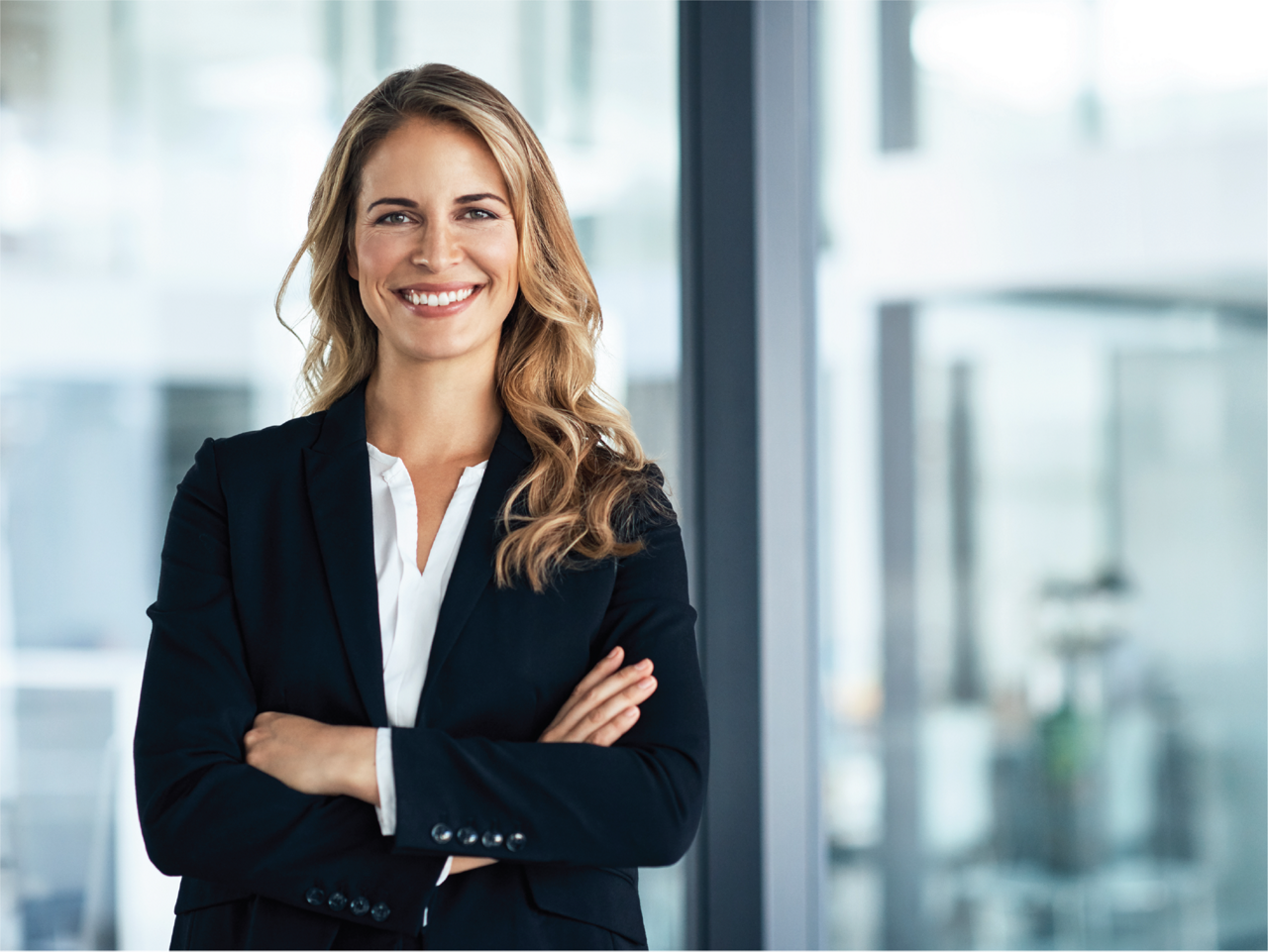 professional woman in a suit with her arms crossed smiling