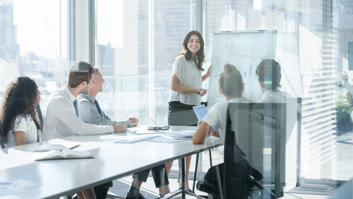 Employee uses whiteboard to present during a meeting to team and executives
