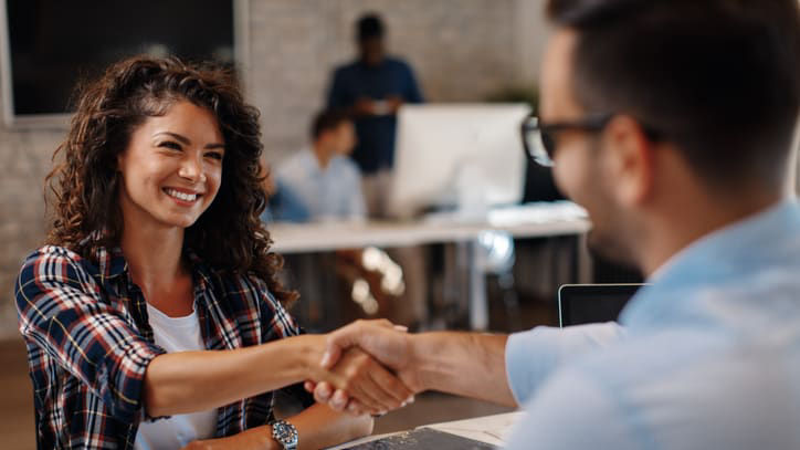 A woman shaking hands with a man in an office.