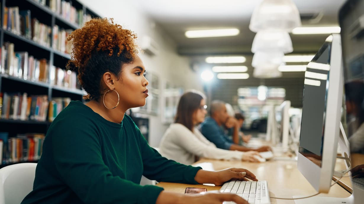 A woman using a computer in a library.