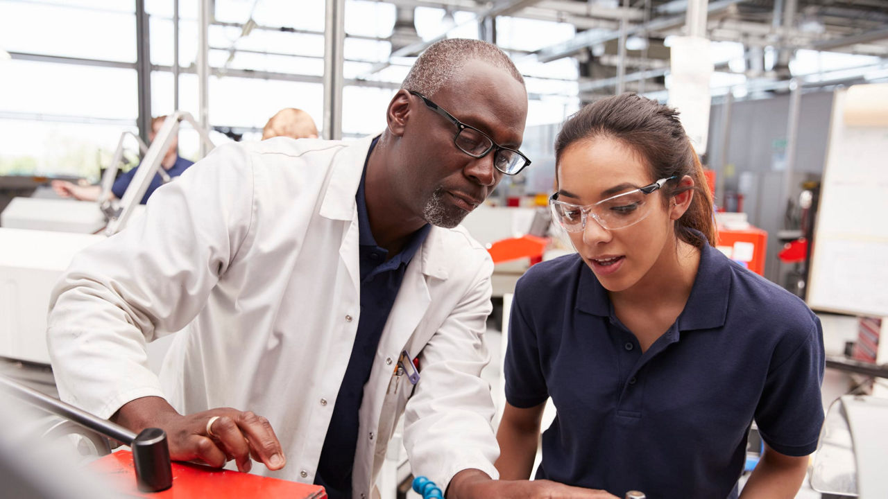 A man and woman working on a machine in a factory.