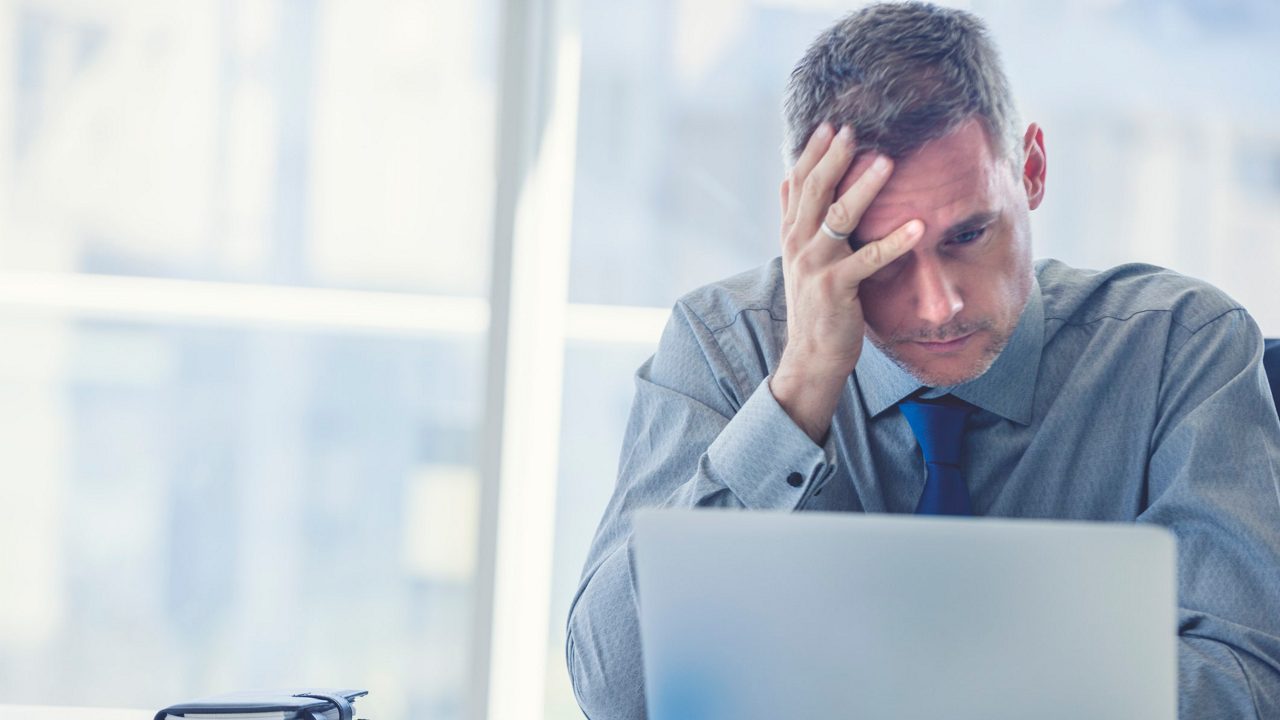 A businessman with his head on his head in front of a laptop.
