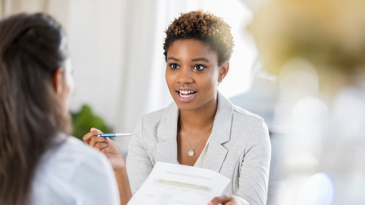 A woman is talking to another woman in an office.