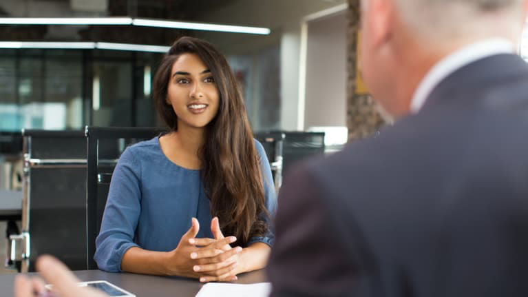A woman is talking to a man in an office.