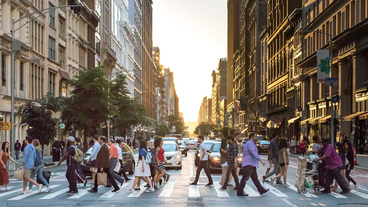 A crowd of people crossing a street in new york city.