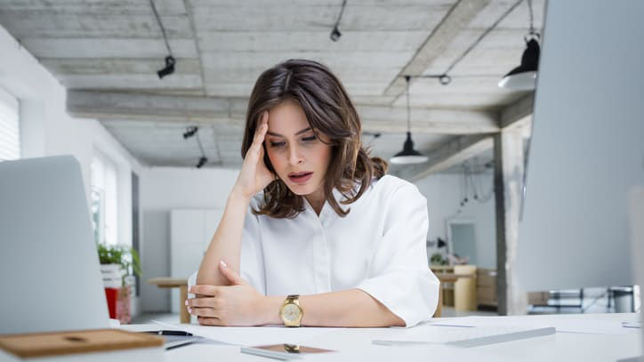 A woman sitting at a desk with her head on her hand.