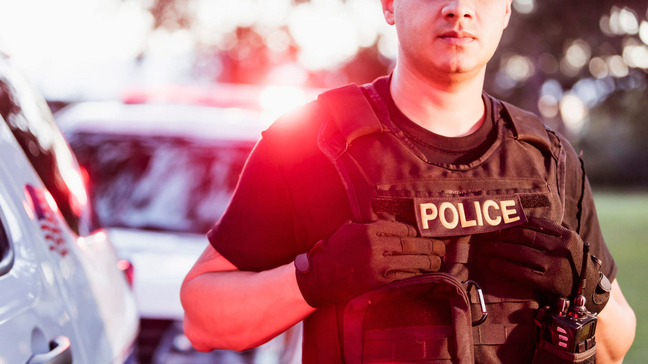 A police officer standing in front of a police car.
