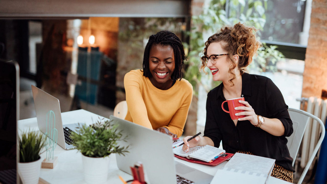 Two women working at a desk in an office.