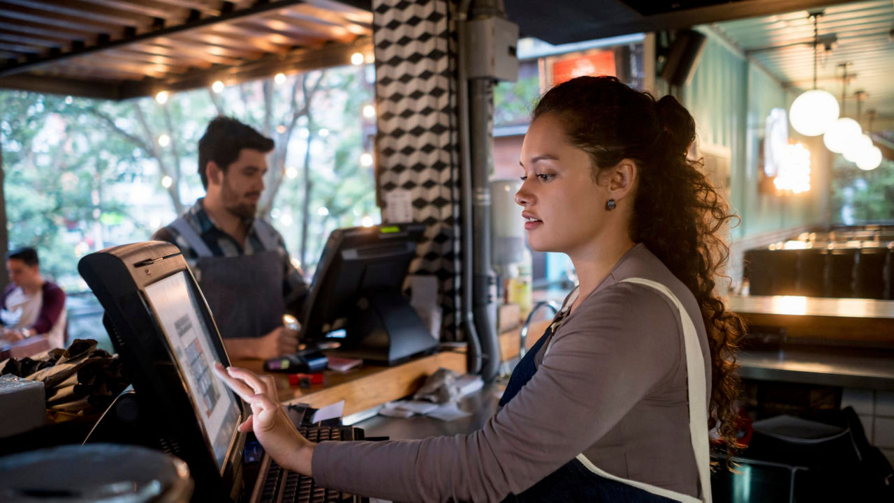 A woman is working at a counter in a restaurant.