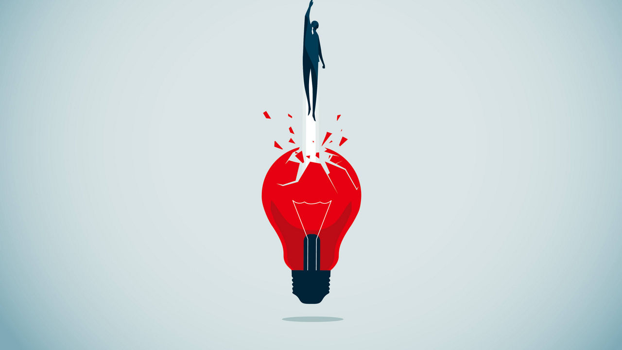 A red light bulb with a person standing on top of it.